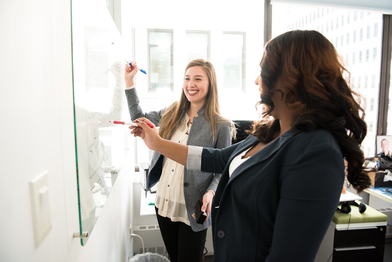 Two colleagues talking through ideas at a whiteboard