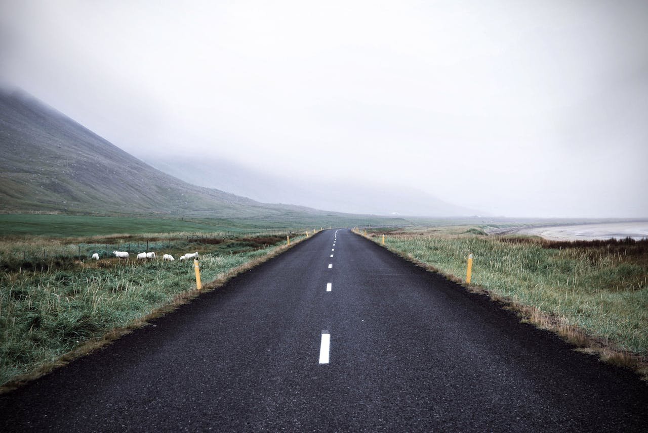A long open road stretching towards misty hills